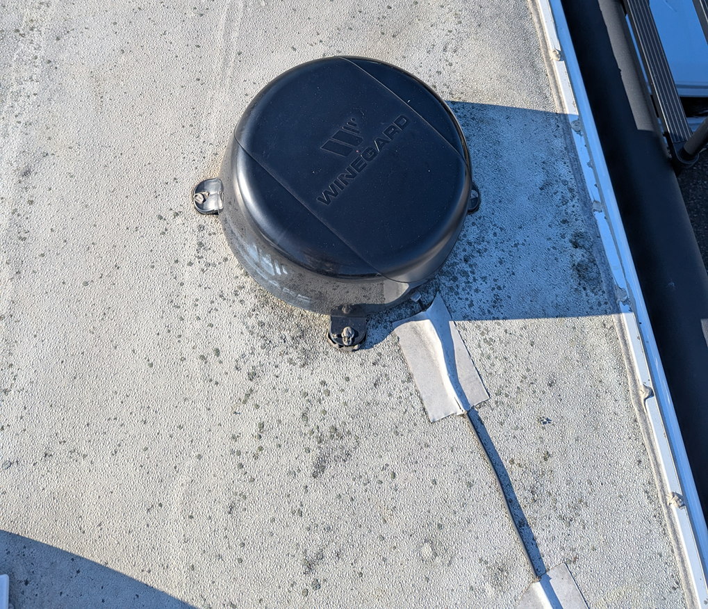 Old RV roof antenna with worn sealant before roof replacement
